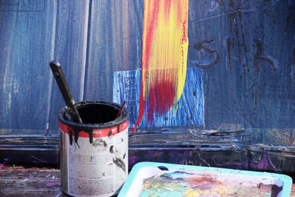 Open paint can with brush draining to minimise waste before sealing for storage or recycling.